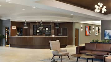 A hotel lobby with a reception desk, seating area, and artwork on the walls.