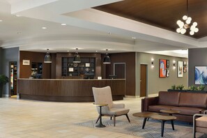 A hotel lobby with a reception desk, seating area, and artwork on the walls.