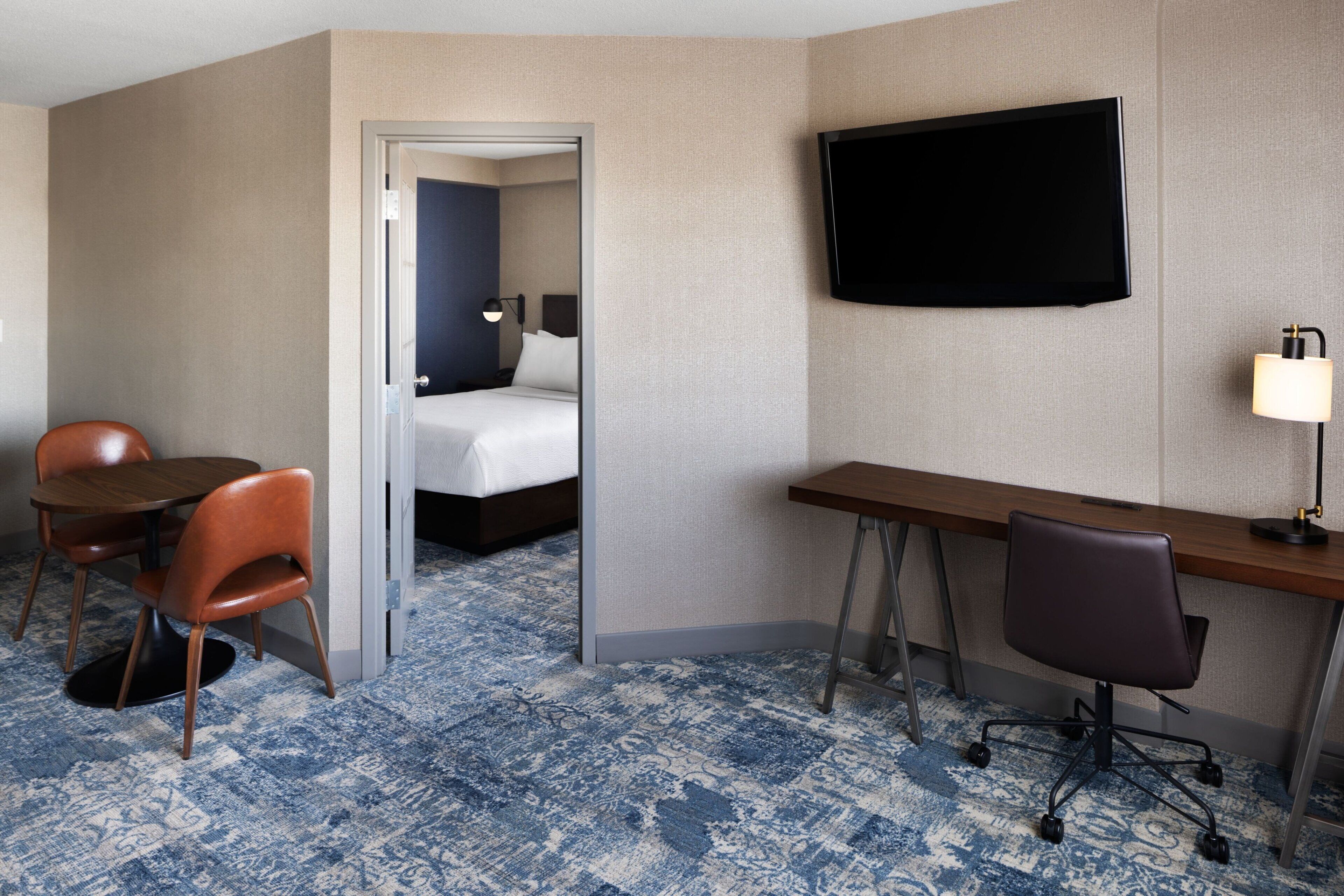 Una habitación de hotel con una cama, un escritorio, una silla, un televisor y una lámpara.