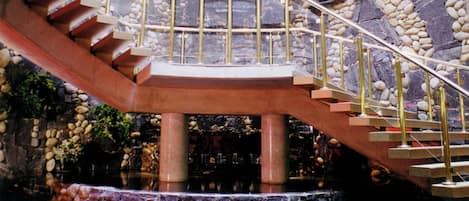 Una imponente escalera con barandilla de cristal que conduce a un techo alto.
