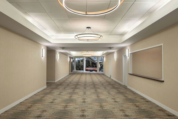 A hotel corridor with a patterned carpet, recessed lighting, and a view of the outdoors. - Four Points by Sheraton Edmonton South (Edmonton)