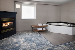 Un baño moderno con bañera, chimenea y estante de madera con toallas.
