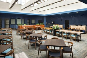 A spacious indoor dining area with multiple seating arrangements including tables and booths, a kitchen area, and a high ceiling with skylights. - Four Points by Sheraton Edmonton South (Edmonton)