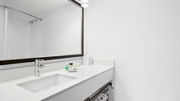 A modern bathroom with a white sink, a mirror, and a showerhead.