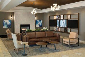 A modern lounge area with a fireplace, leather sofa, armchairs, and a coffee table.
