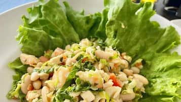 A plate of food with beans and greens, served on a white plate with lettuce leaves on the side.