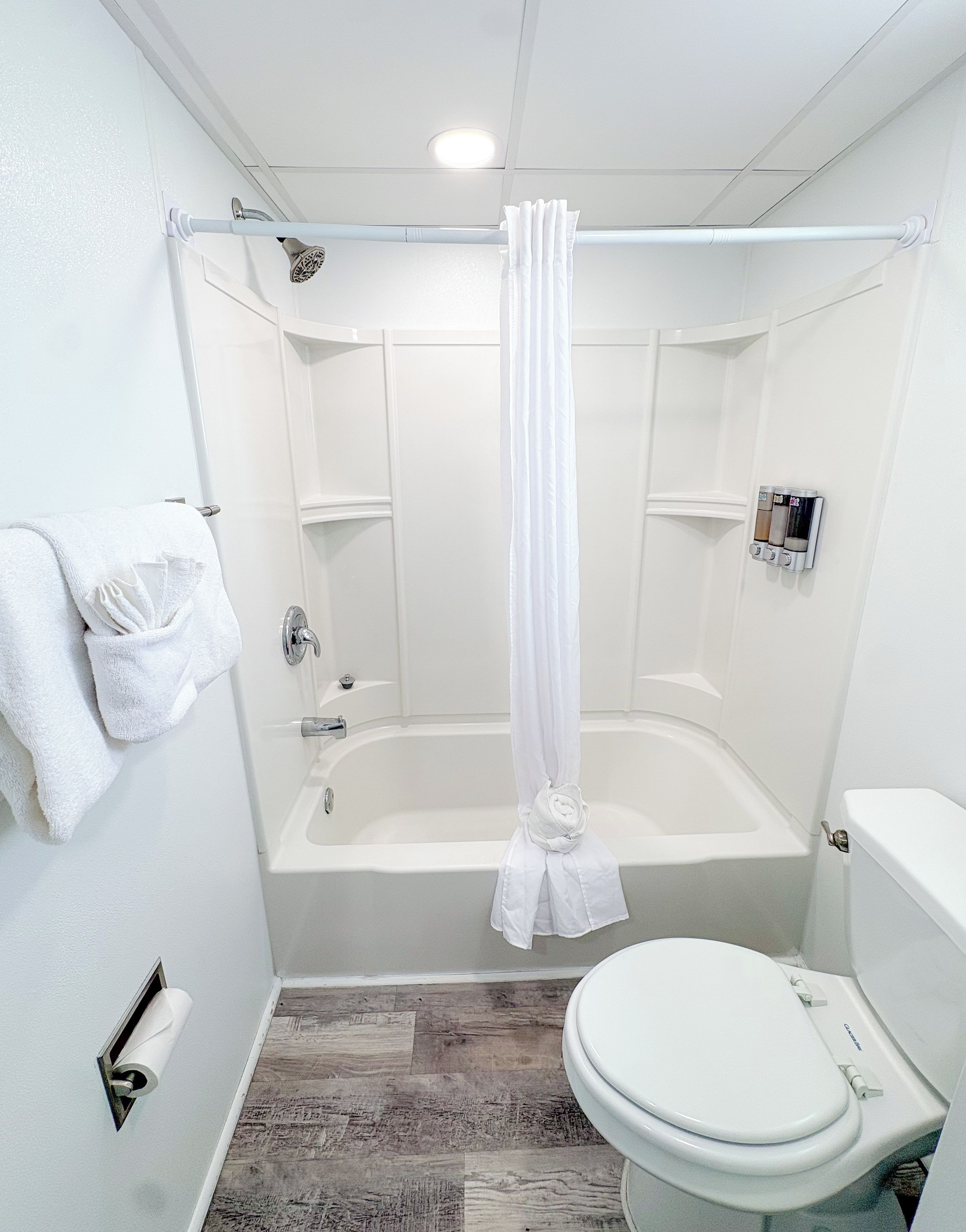 A bathroom with a bathtub, toilet, and shower curtain.