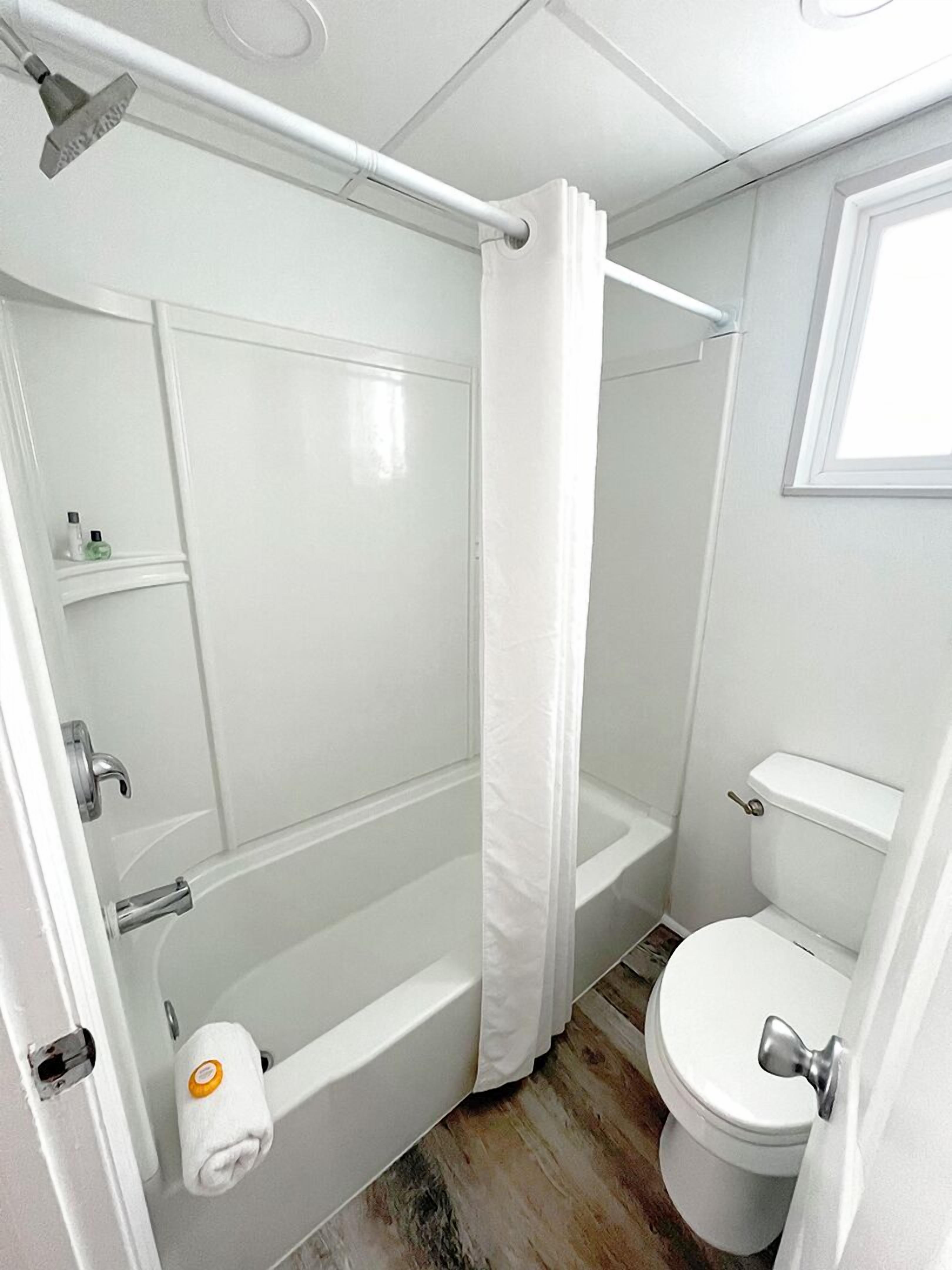 A compact bathroom with a bathtub, toilet, and shower curtain.