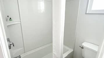 A compact bathroom with a bathtub, toilet, and shower curtain.