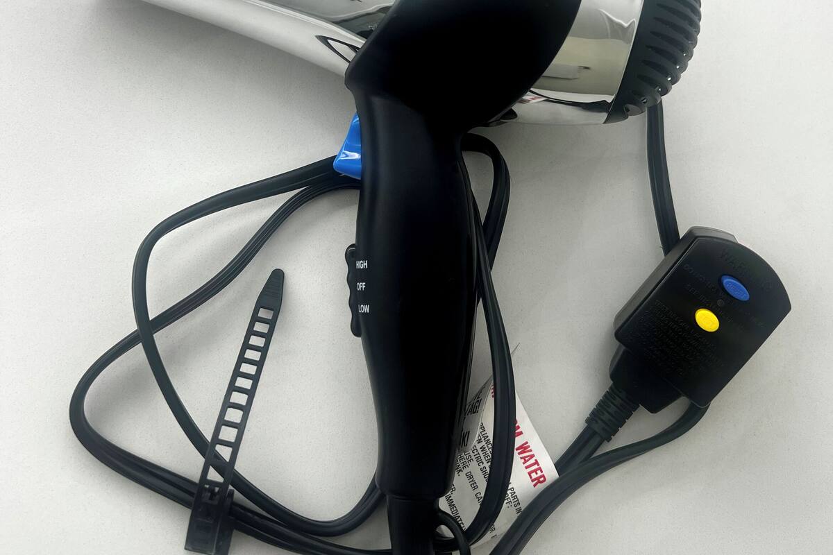 A hair dryer with a cord and a power adapter on a white surface.
