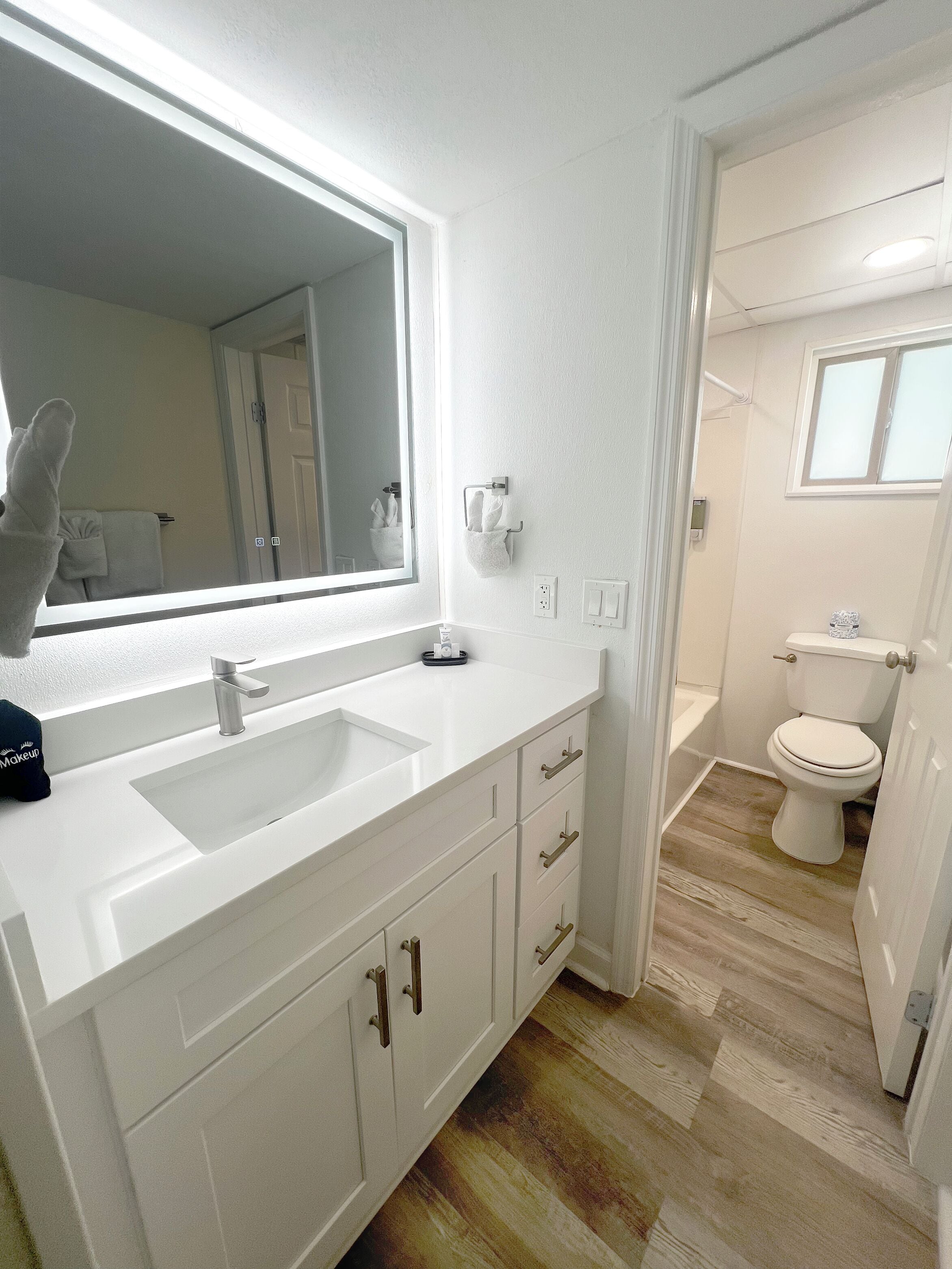 A modern bathroom with a large mirror, white vanity, and a toilet.