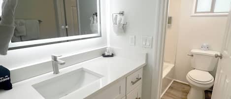 A modern bathroom with a large mirror, white vanity, and a toilet.