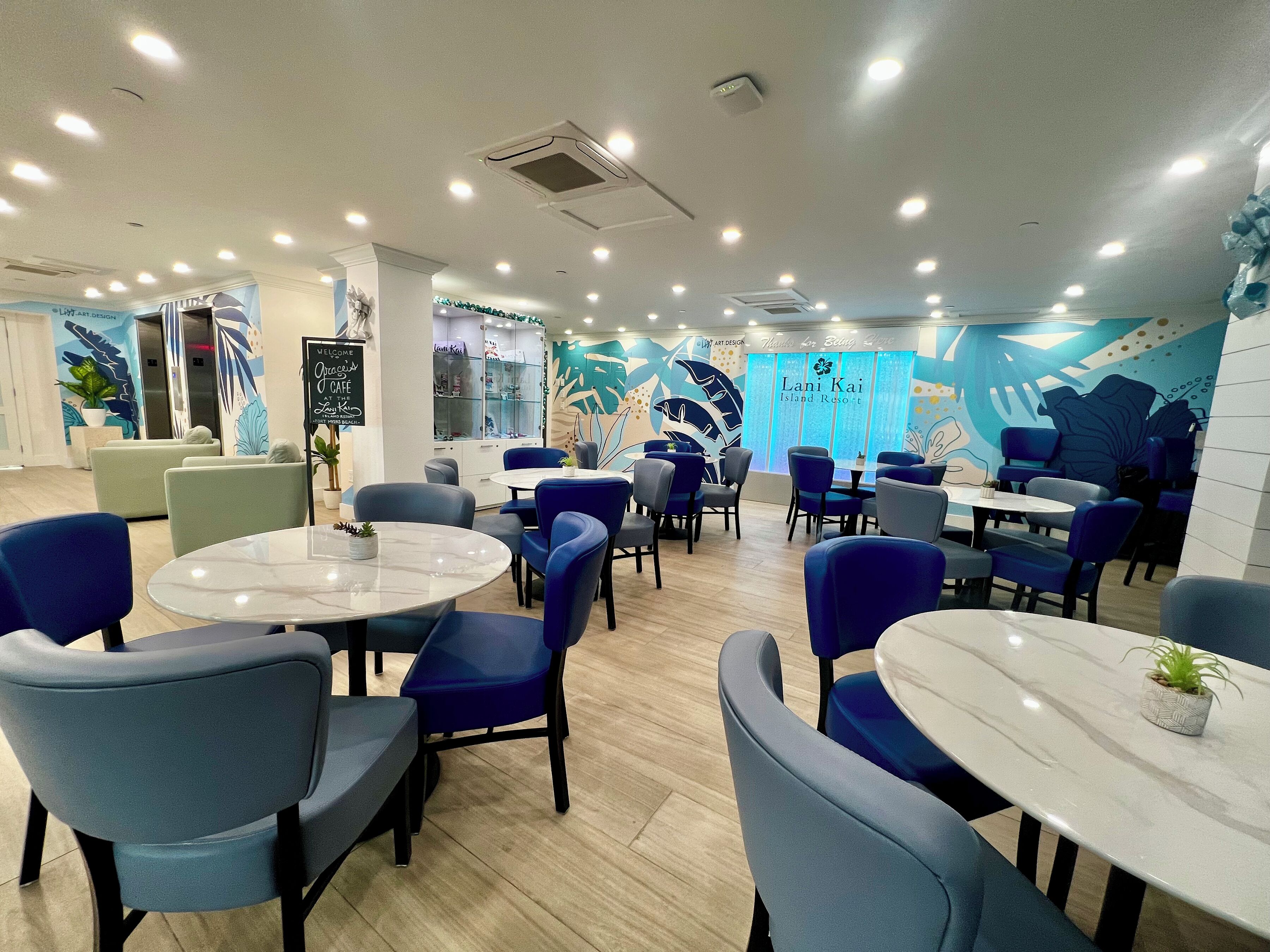 A modern restaurant with round tables and blue chairs, featuring a mural of a whale and a sign for 'Lani Kai Island Resort'.
