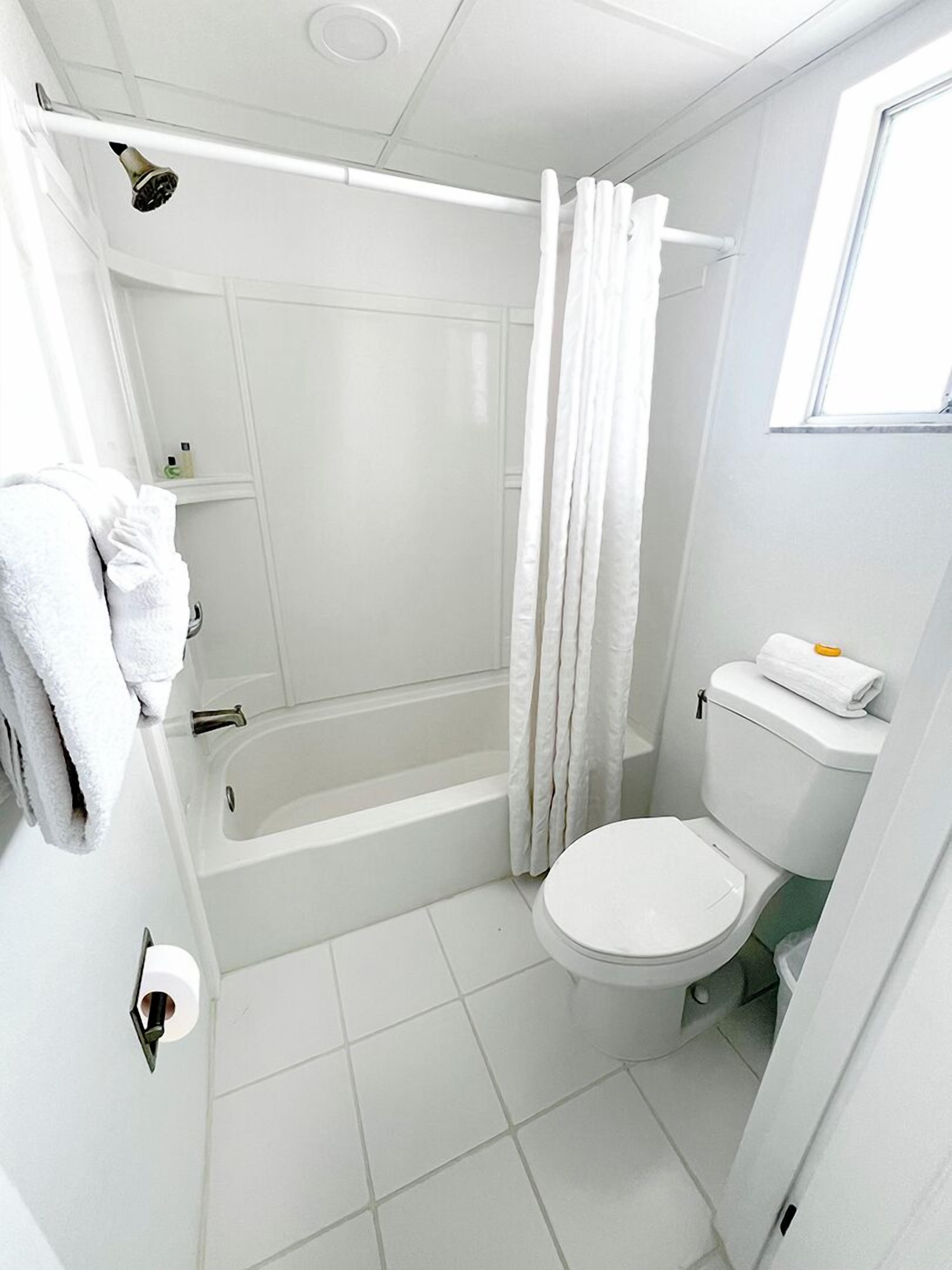 Un baño con bañera, inodoro y cortina de ducha.