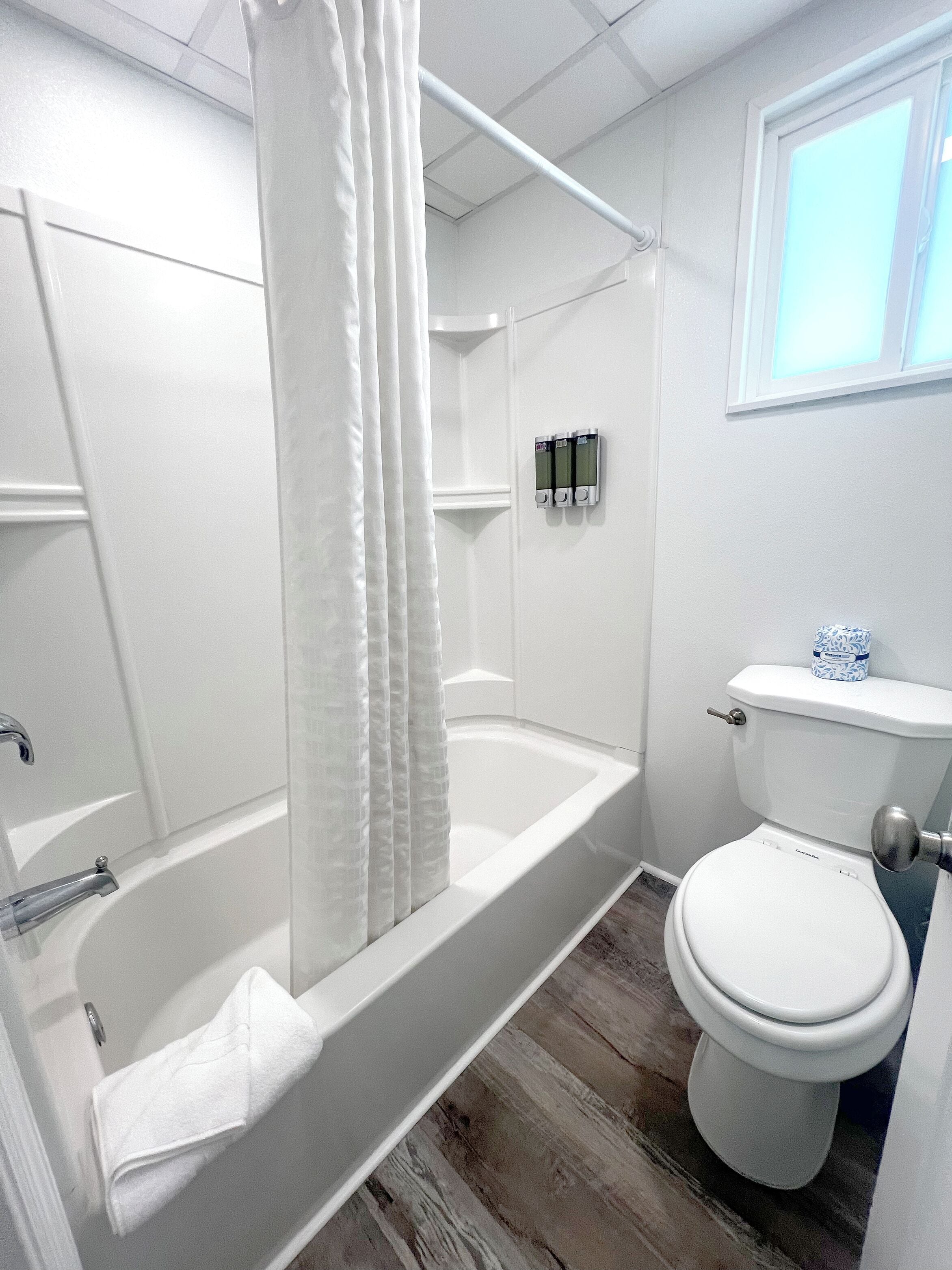 A bathroom with a bathtub, toilet, and shower curtain.