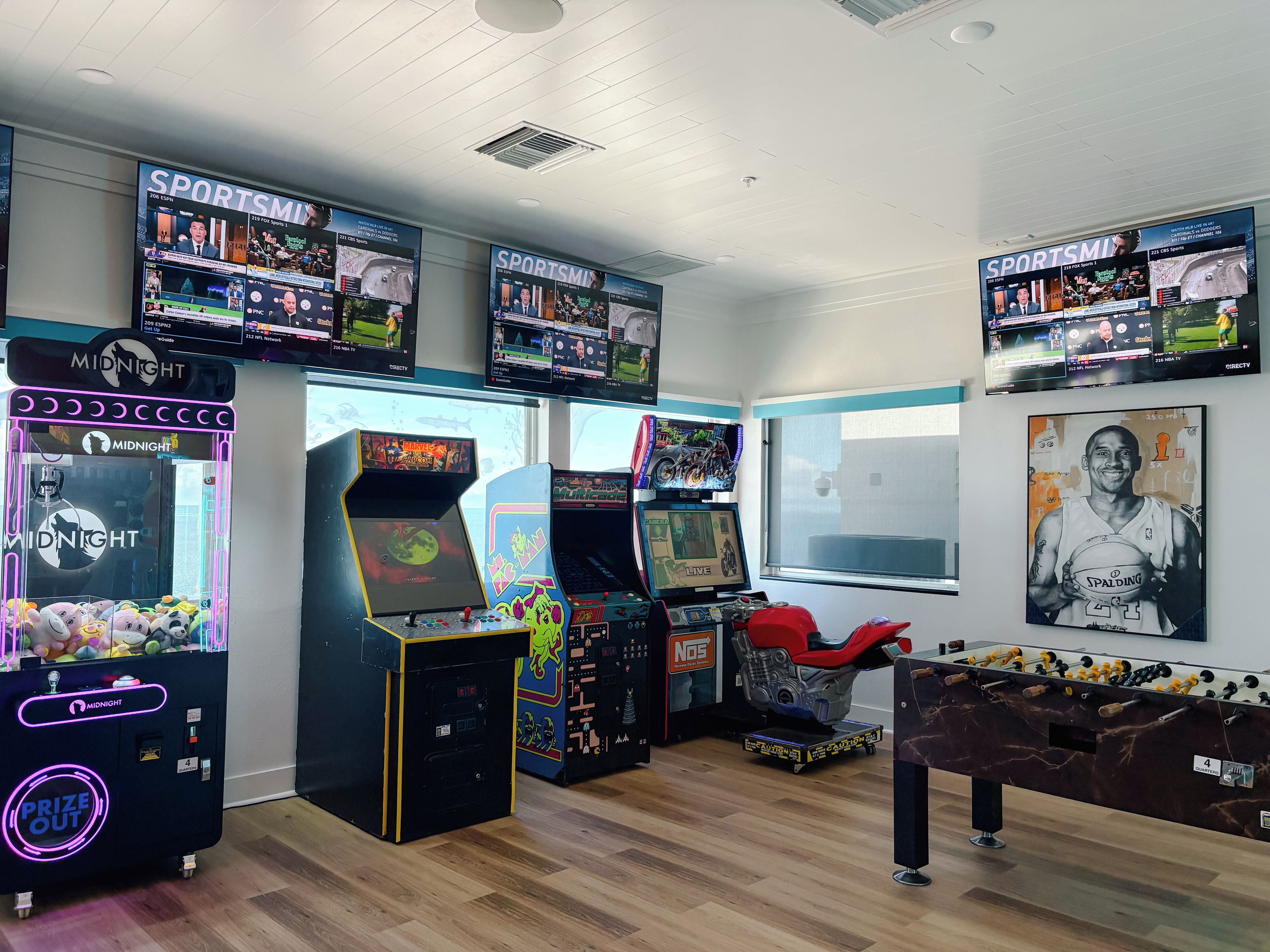 Een ruimte met meerdere speelautomaten, waaronder grijpkranen en spelautomaten, plus een tafelvoetbaltafel.
