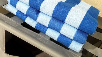 Una toalla azul y blanca a rayas doblada sobre una silla de metal con un cojín color crema.