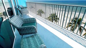 Un balcón con muebles de mimbre que da a una playa.