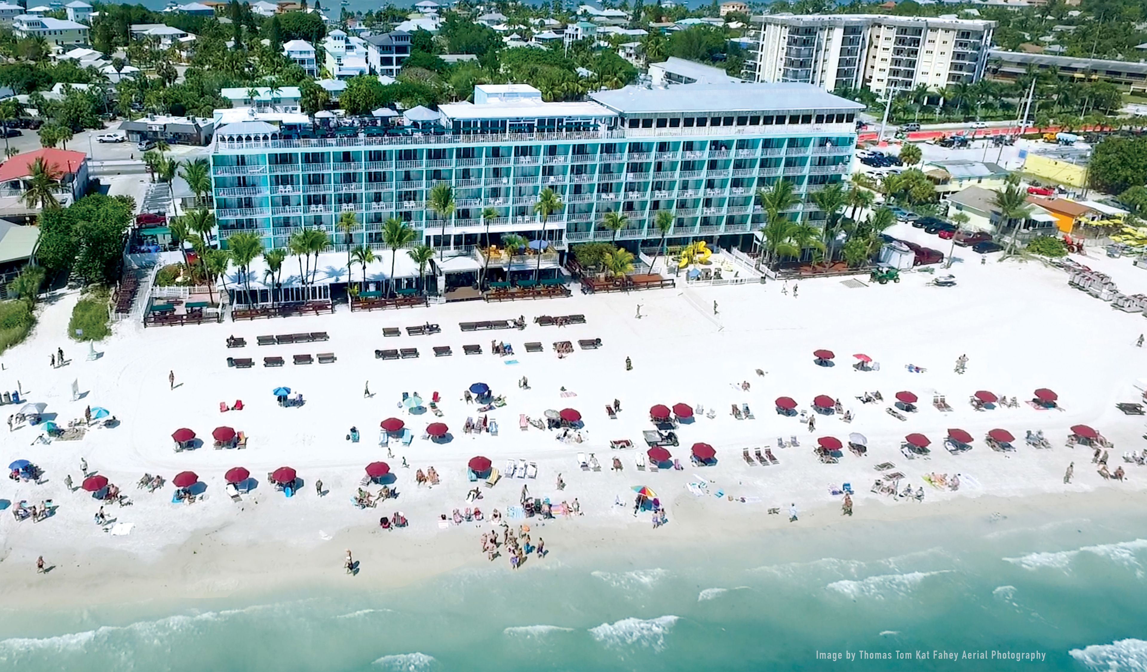 An aerial view of a beach with a hotel in the background.