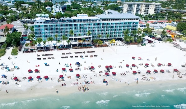 An aerial view of a beach with a hotel in the background.