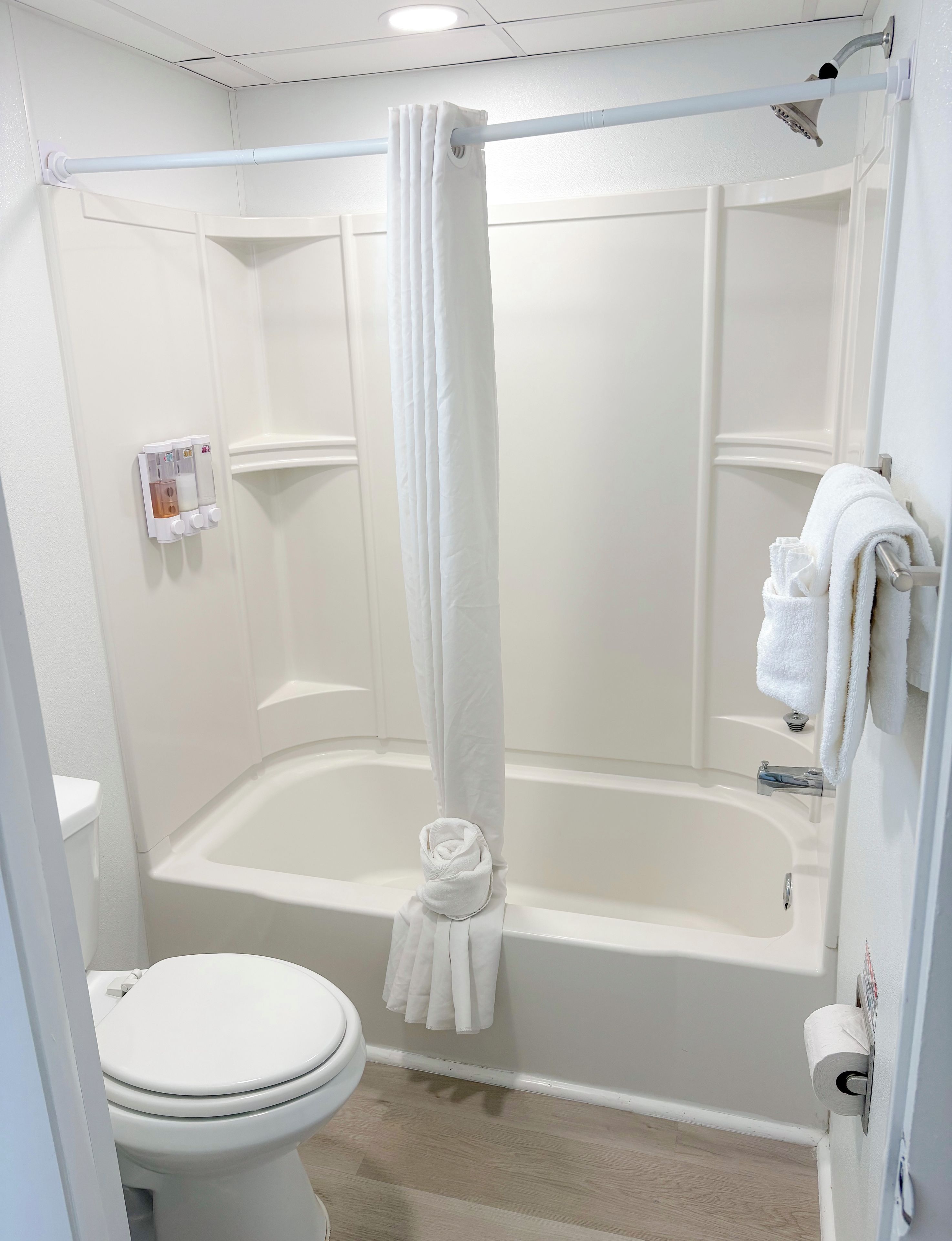A bathroom with a bathtub, toilet, shower curtain, and towel rack.