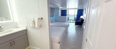 A modern hotel room with a bathroom, a balcony with a view, and a seating area.