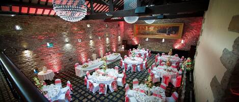 A banquet hall with round tables, white tablecloths, and red sashes.