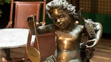 A bronze statue of a seated figure holding a chain and a circular object with the word "Atrium" on it.