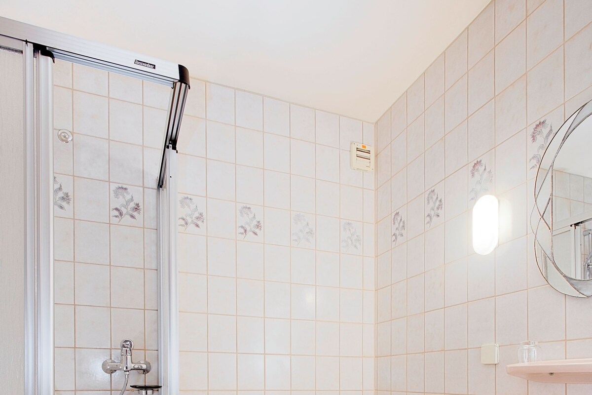 Un baño con ducha, inodoro, lavamanos y cabina de ducha con mampara de vidrio.