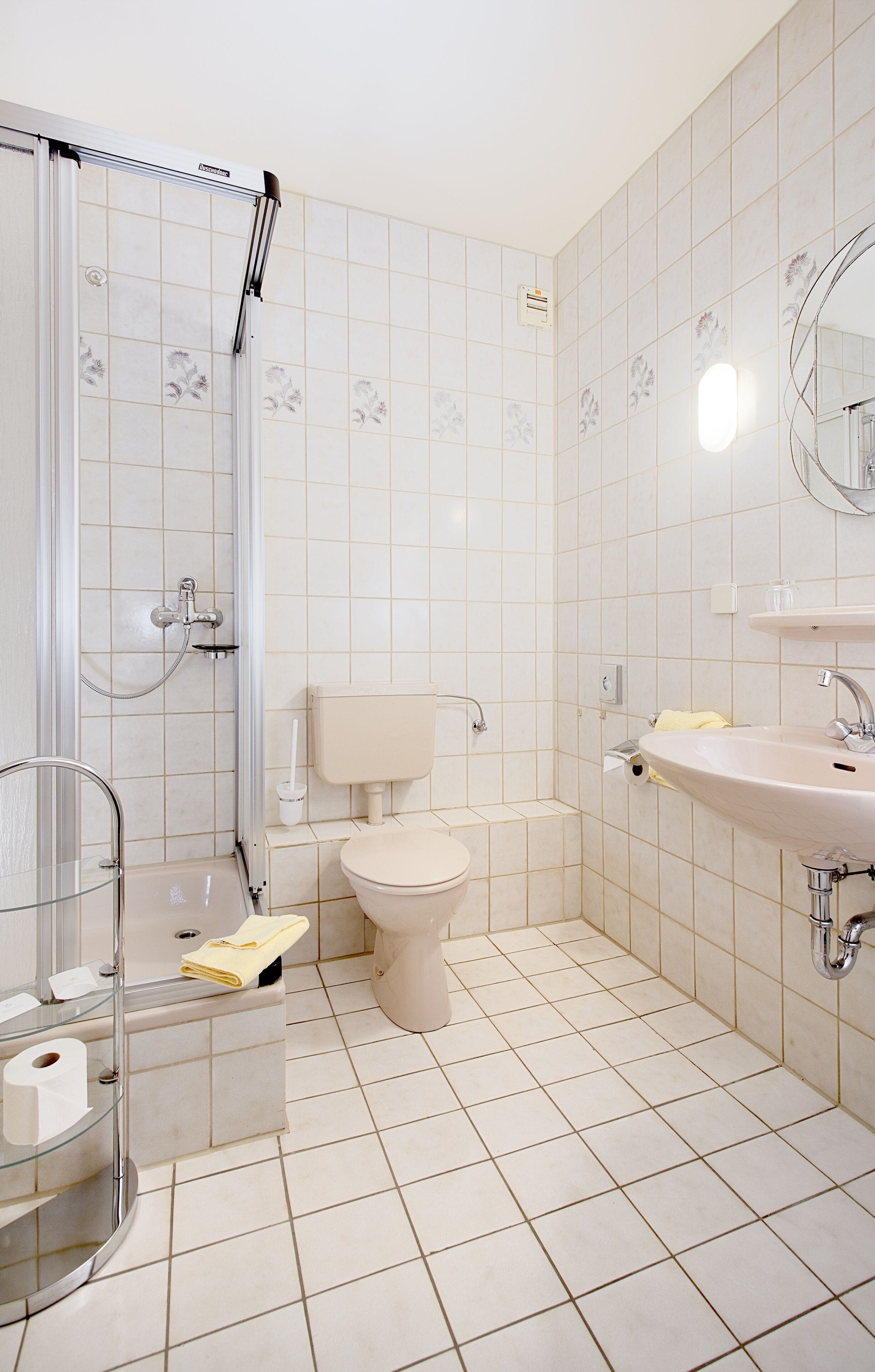 Un baño con ducha, inodoro, lavamanos y cabina de ducha con mampara de vidrio.