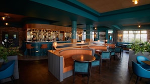 Een bar met zitplaatsen en een toog, met houten meubels en een bakstenen muur.