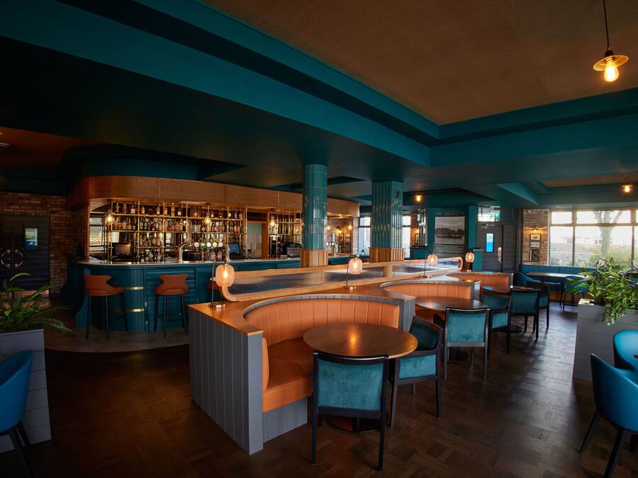 Eine Bar mit Sitzgelegenheiten und einer Theke, ausgestattet mit Holzmöbeln und einer Ziegelwand.