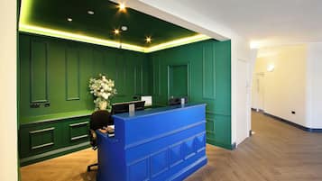 Un área de recepción con mostrador azul, paredes verdes y piso de madera.
