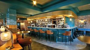 Een bar met een gebogen toonbank, meerdere krukken en diverse flessen en glazen.