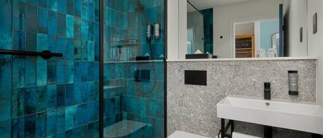 Un baño moderno con cabina de ducha de vidrio, un lavabo blanco y un espejo encima.