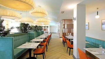 A restaurant with teal booths, orange chairs, and a wooden floor.