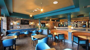 A restaurant with blue booths, wooden tables, and a bar area.