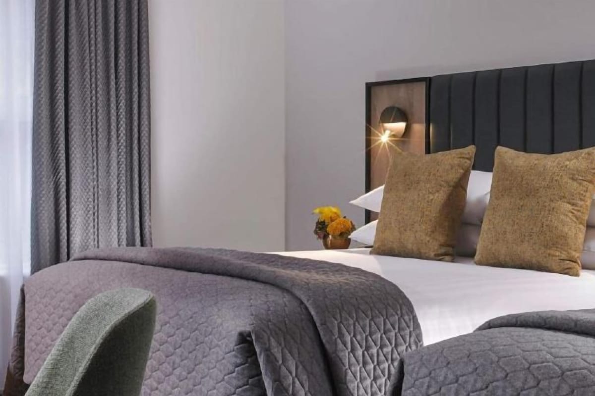 A hotel room with a bed, a headboard, and a nightstand with a lamp.