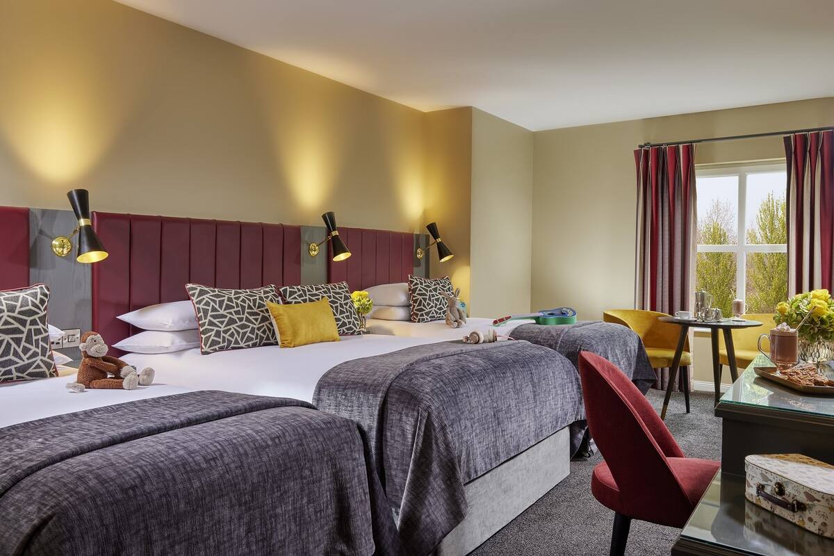 A hotel room with a large bed, two bedside tables, a desk, and a chair.