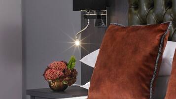 Un dormitorio con una cama, una mesita de noche, una lámpara y un florero decorativo con flores.