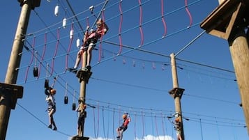 Ein Outdoor-Parcours mit Teilnehmern, die über Hängebänder und Plattformen navigieren.