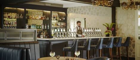 A bar area with leather seating, a bartender, and a well-stocked liquor shelf.