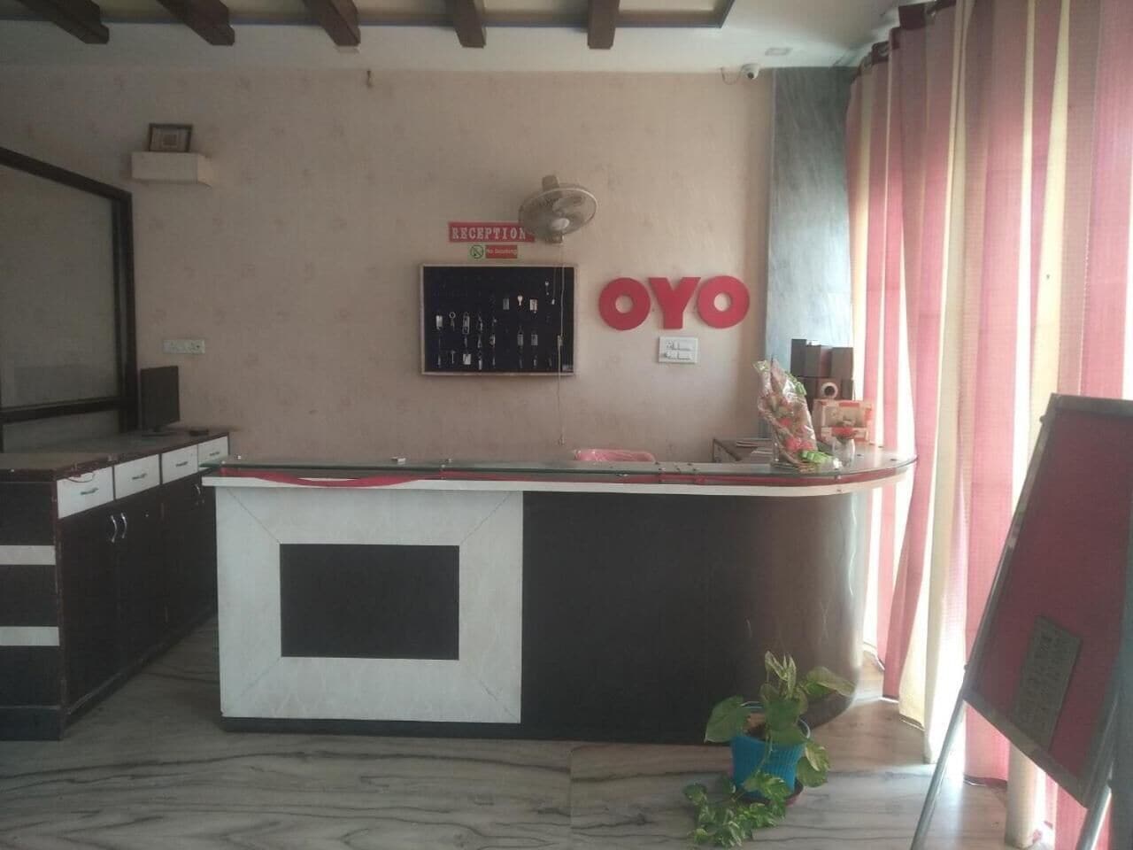 Uma área de recepção com balcão, uma placa com a palavra 'Recepção' e uma placa com a inscrição 'OYO' em letras vermelhas.