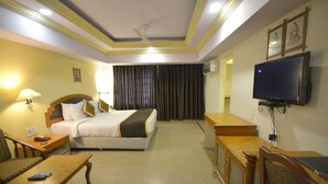 Ein Hotelzimmer mit einem Bett, einem Schreibtisch, einem Sessel, einem Fernseher und einer Lampe.