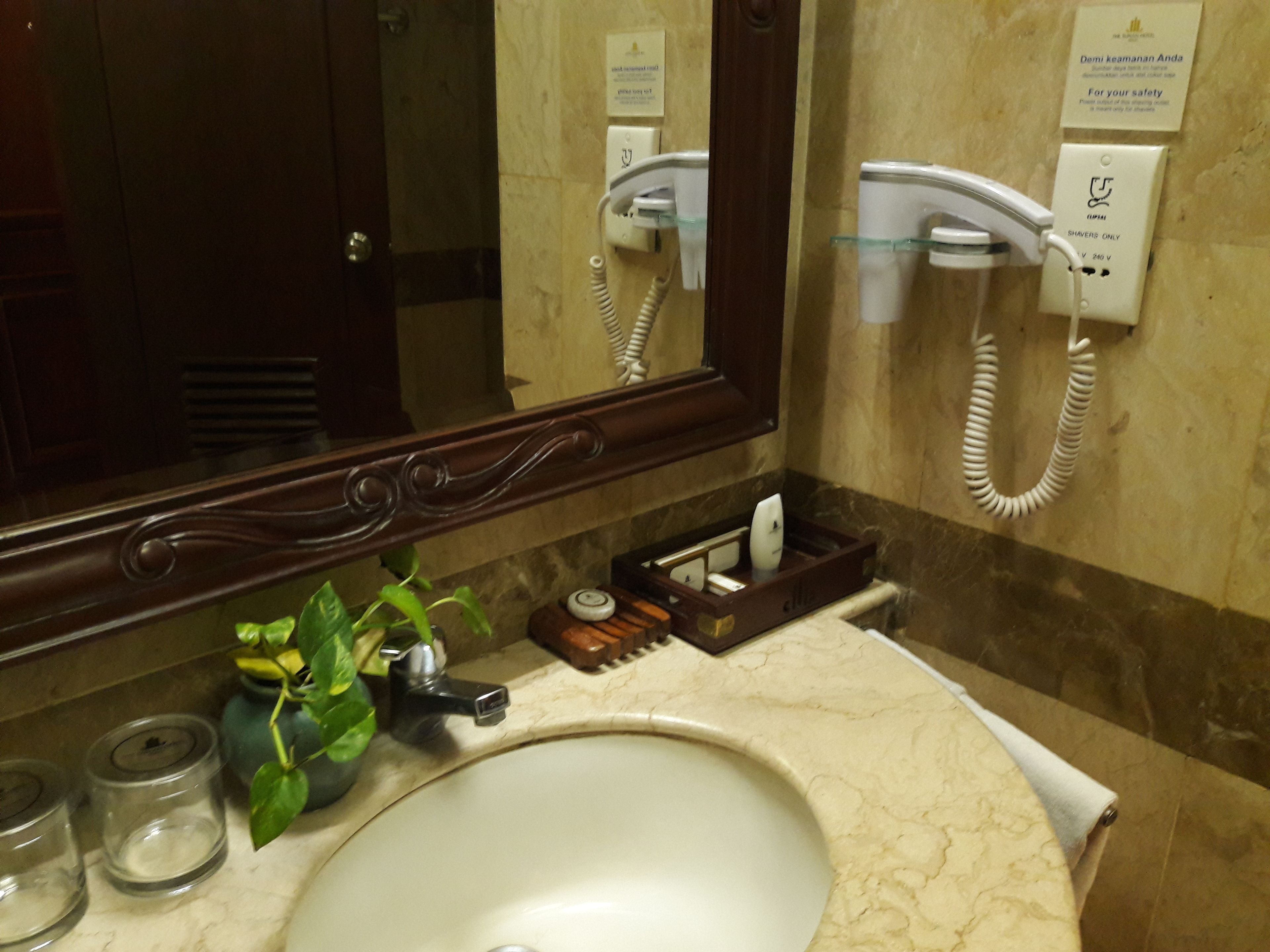 A bathroom with a marble sink, a mirror, a hairdryer, and a telephone.