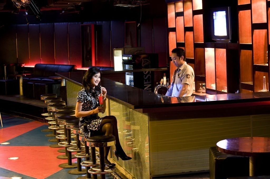A bar area with stools, a counter, and a television screen.