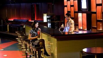 A bar area with stools, a counter, and a television screen.