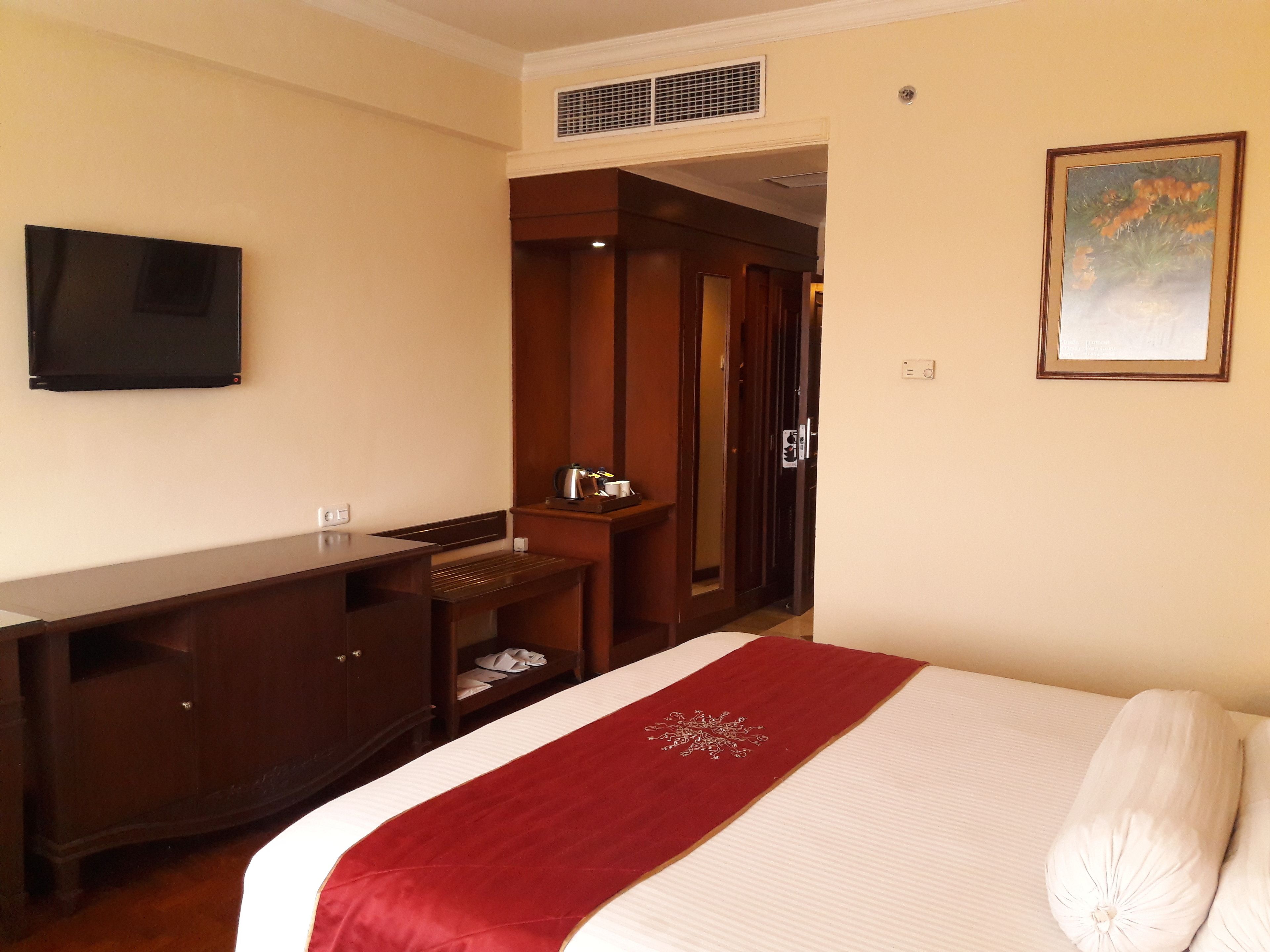 Una camera d'albergo con un letto, una scrivania, una televisione e un armadio.