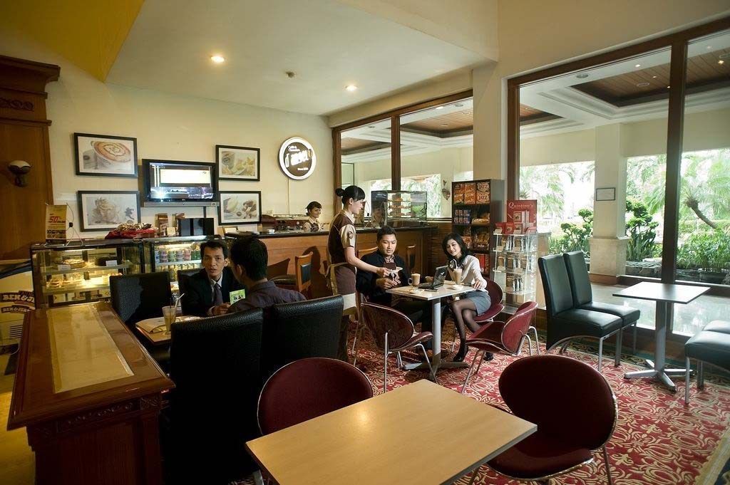 Un restaurante con zona de bar, diversas opciones de asientos, incluyendo cabinas y mesas, y vistas al exterior a través de amplios ventanales.