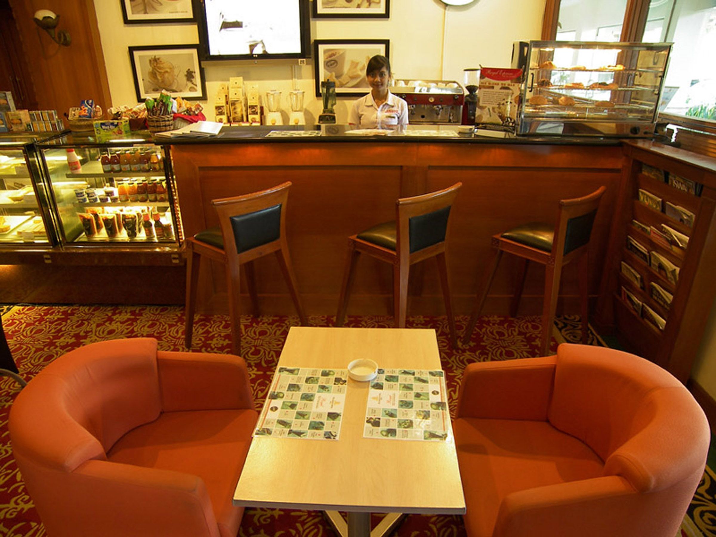 Um espaço de bar acolhedor, com balcão, cadeiras e uma mesa com um jogo de tabuleiro.